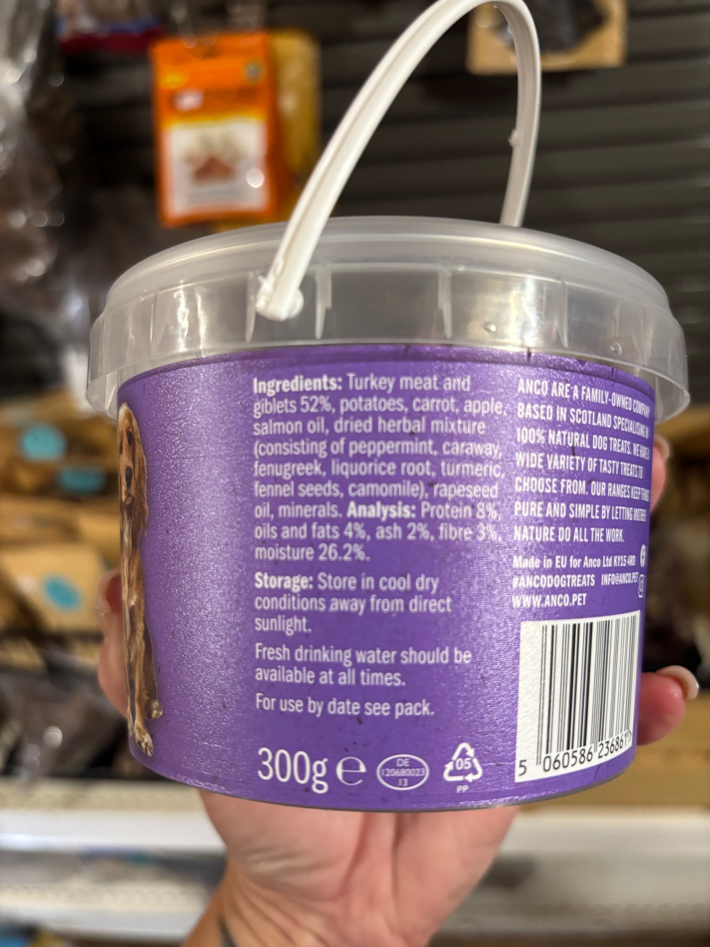 Hand holding a container with a purple label, blurred background